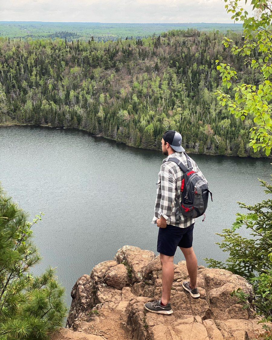 Andrew on a rocky overlook above a lake on a hike